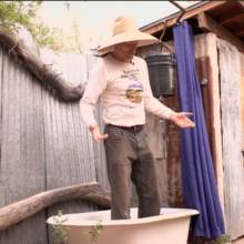 Rainwater harvester Brad Lancaster stands in his outdoor bathtub plumbed to water his fruit trees.